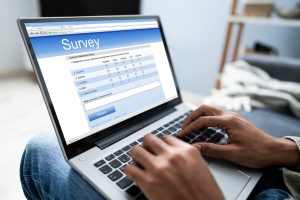 Close-up Of Person On Sofa With Laptop Showing Survey Form