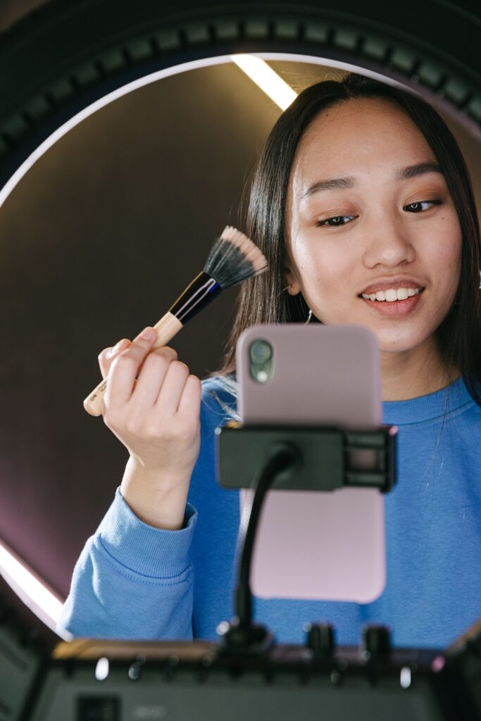 alt=woman-putting-on-makeup-in-front-of-phone