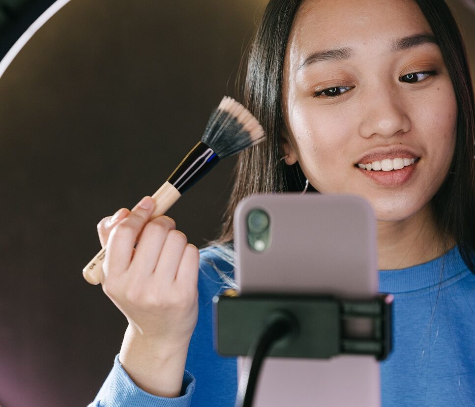 alt=woman-putting-on-makeup-in-front-of-phone